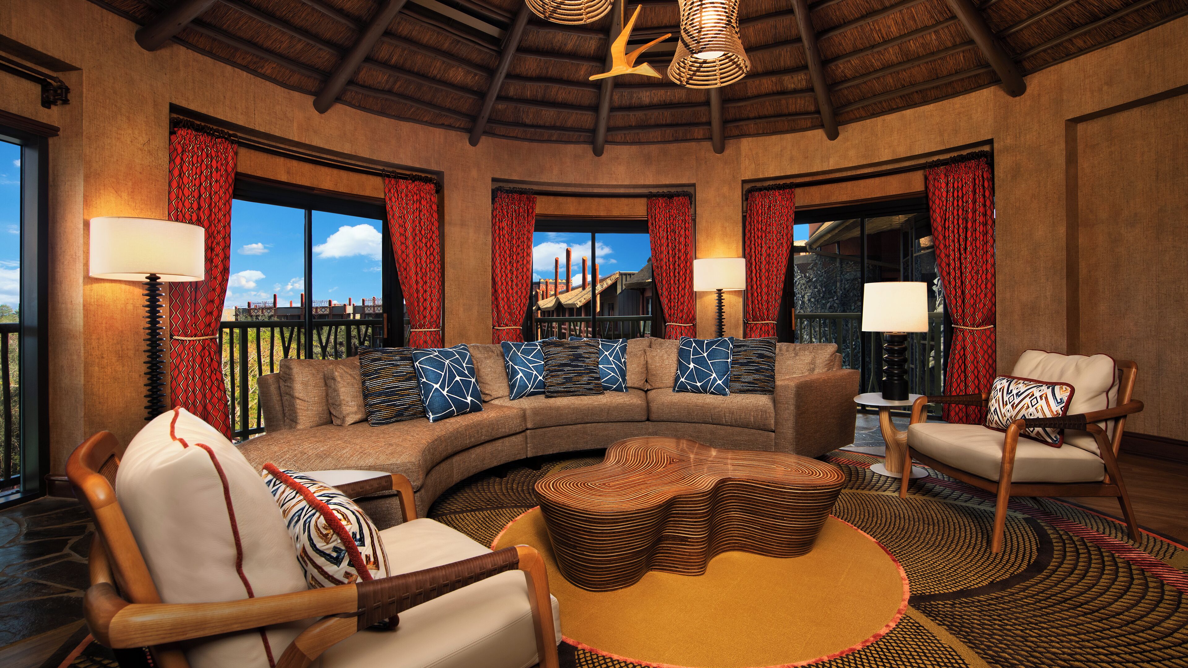 A cozy lounge area with a curved sofa, two armchairs, a coffee table, and a patterned rug.