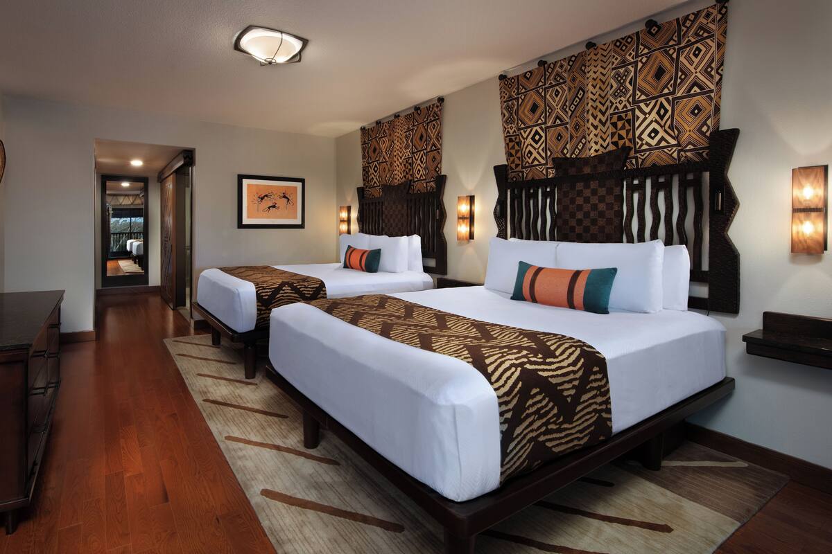 A hotel room with two beds, a TV, and a wooden dresser.