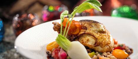 Une assiette contenant un plat composé de poulet rôti, de légumes et d’une feuille décorative.