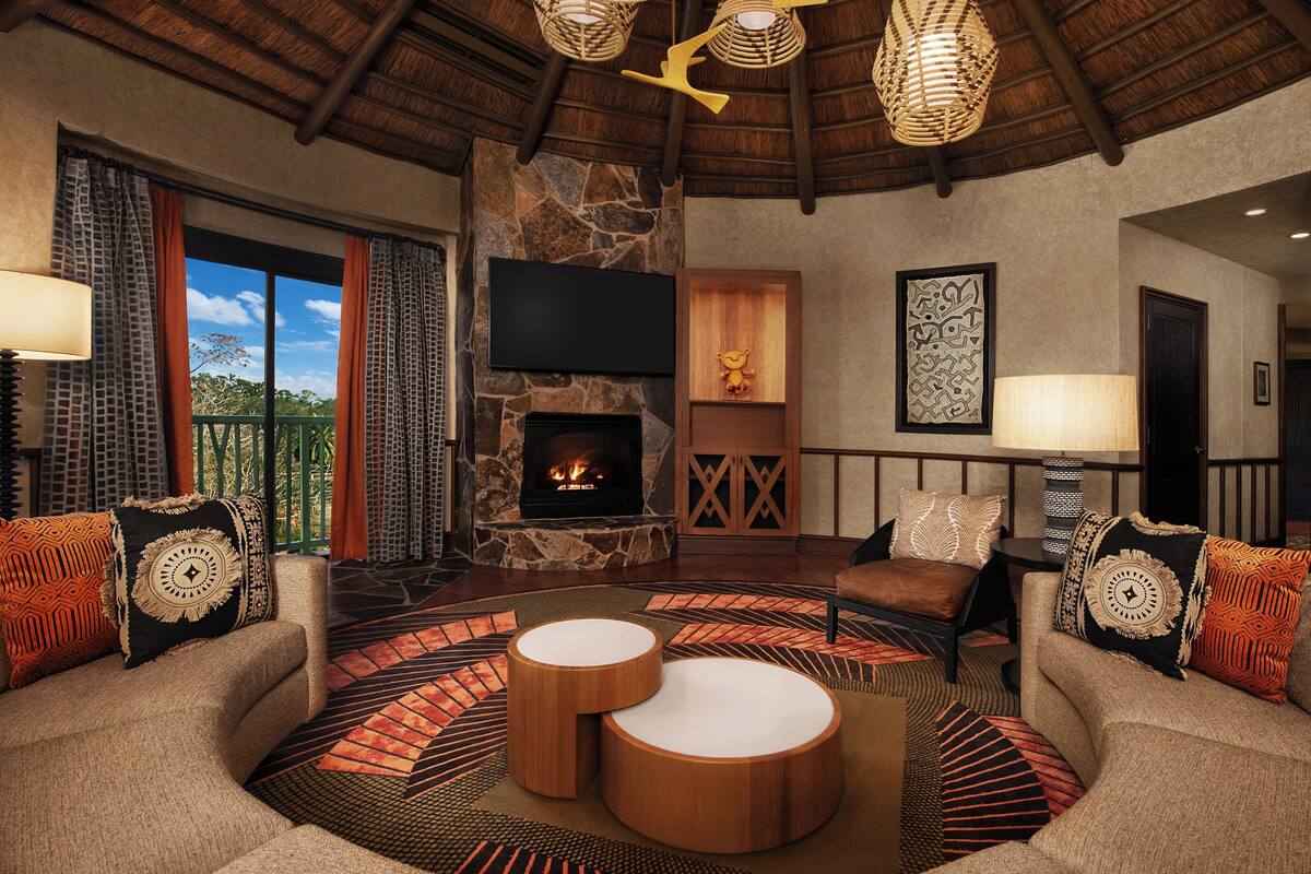 A cozy living room with a stone fireplace, comfortable seating, and a large window overlooking greenery.