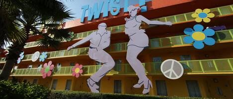A hotel facade with the name 'TWIST!' and a dance-themed mural.
