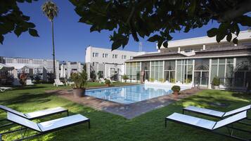 Una piscina al aire libre, sillones reclinables de piscina