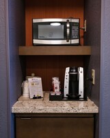 Una kitchenette equipada con microondas, cafetera y dispensador de cápsulas de café Keurig.