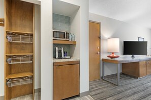 A hotel room with a kitchenette, a microwave, a coffee maker, and a television. - Hilton Garden Inn Atlanta Northpoint (Alpharetta)