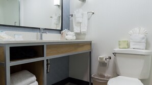 A modern bathroom with a wooden vanity, a large mirror, a toilet, and a towel rack. - Hilton Garden Inn Atlanta Northpoint (Alpharetta)