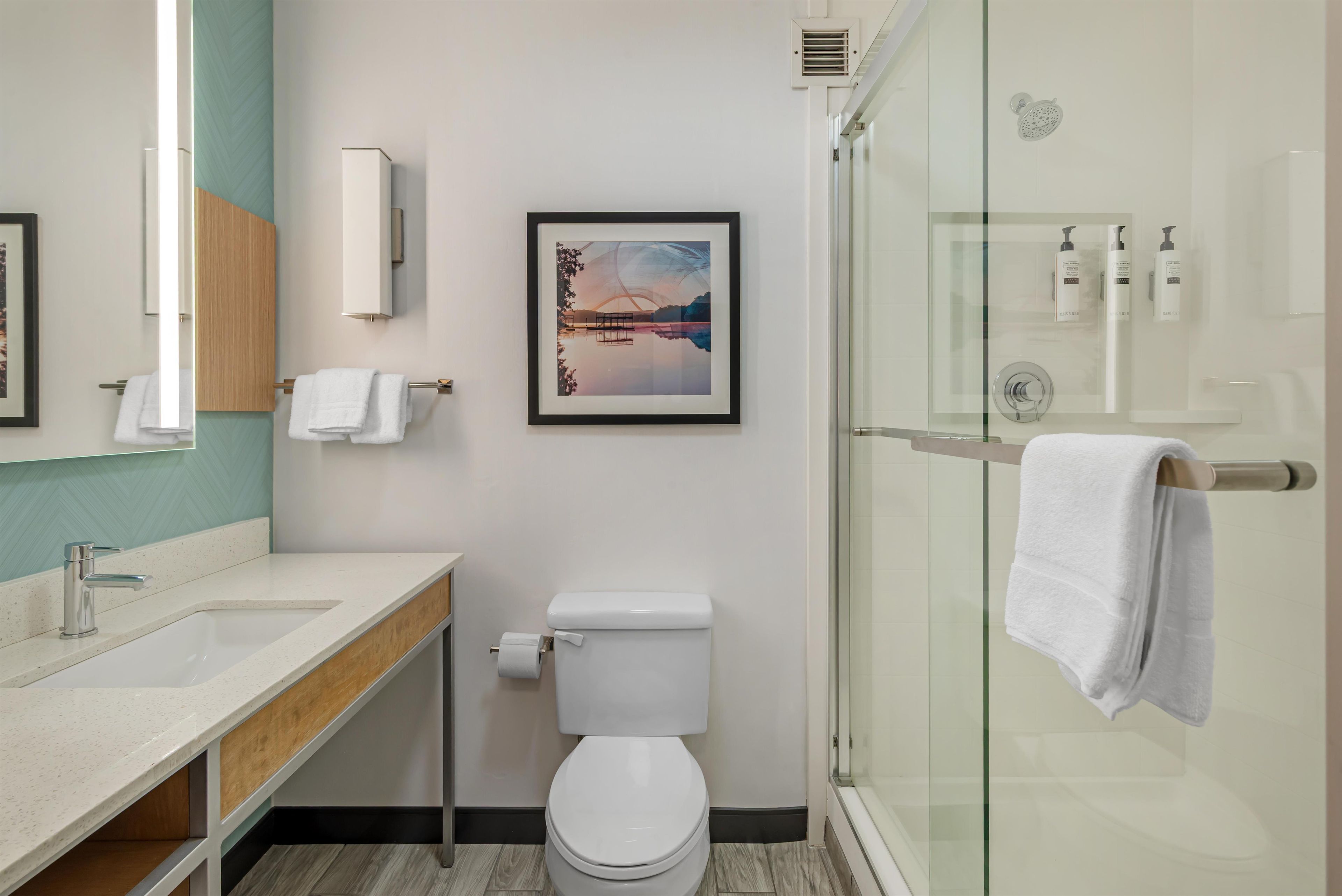 A modern bathroom with a toilet, sink, and shower.