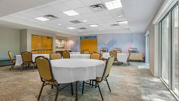 A conference room with round tables, chairs, and a large window.