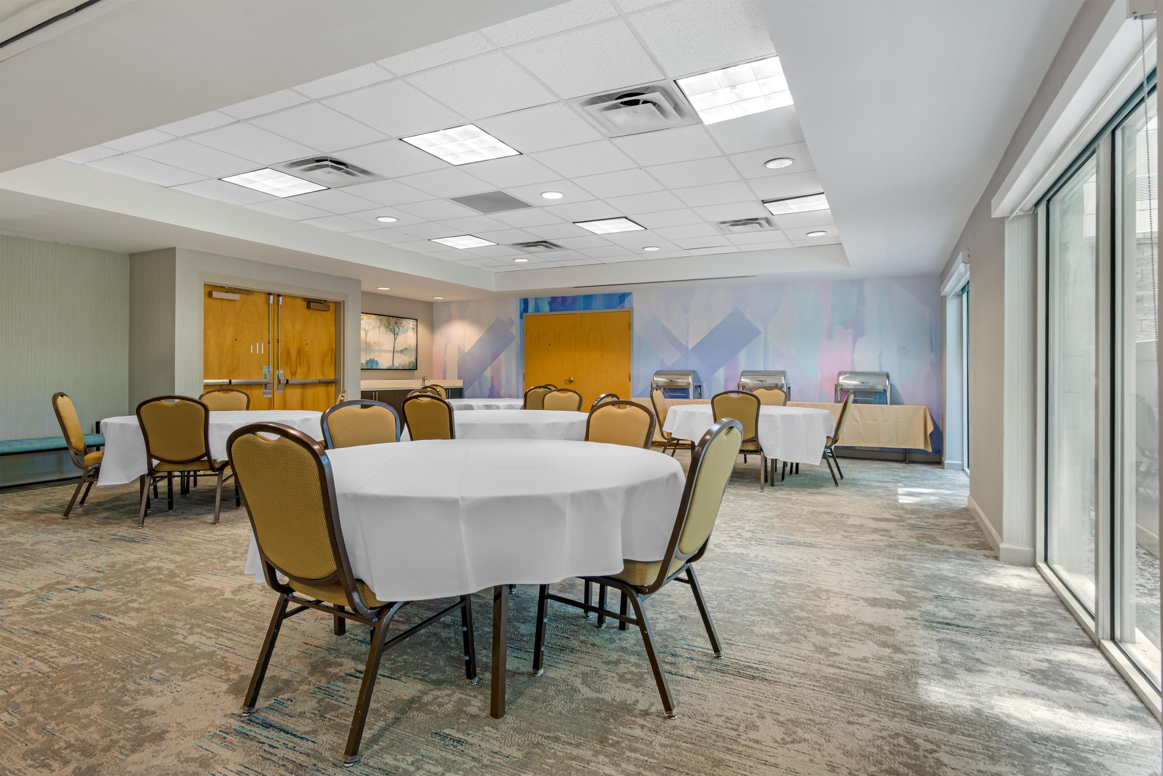 A conference room with round tables, chairs, and a large window.