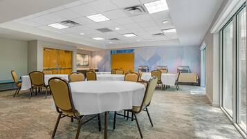 A conference room with round tables, chairs, and a large window.