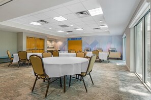 Una sala conferenze con tavoli rotondi, sedie e un'ampia finestra.
