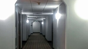 A narrow, well-lit hallway with a patterned carpet, white walls, and a ceiling with recessed lighting. - Comfort Inn Owasso - Tulsa (Owasso)