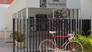 Entrada de hotel con señal de punto de ciclismo, una bicicleta roja y una valla de metal.