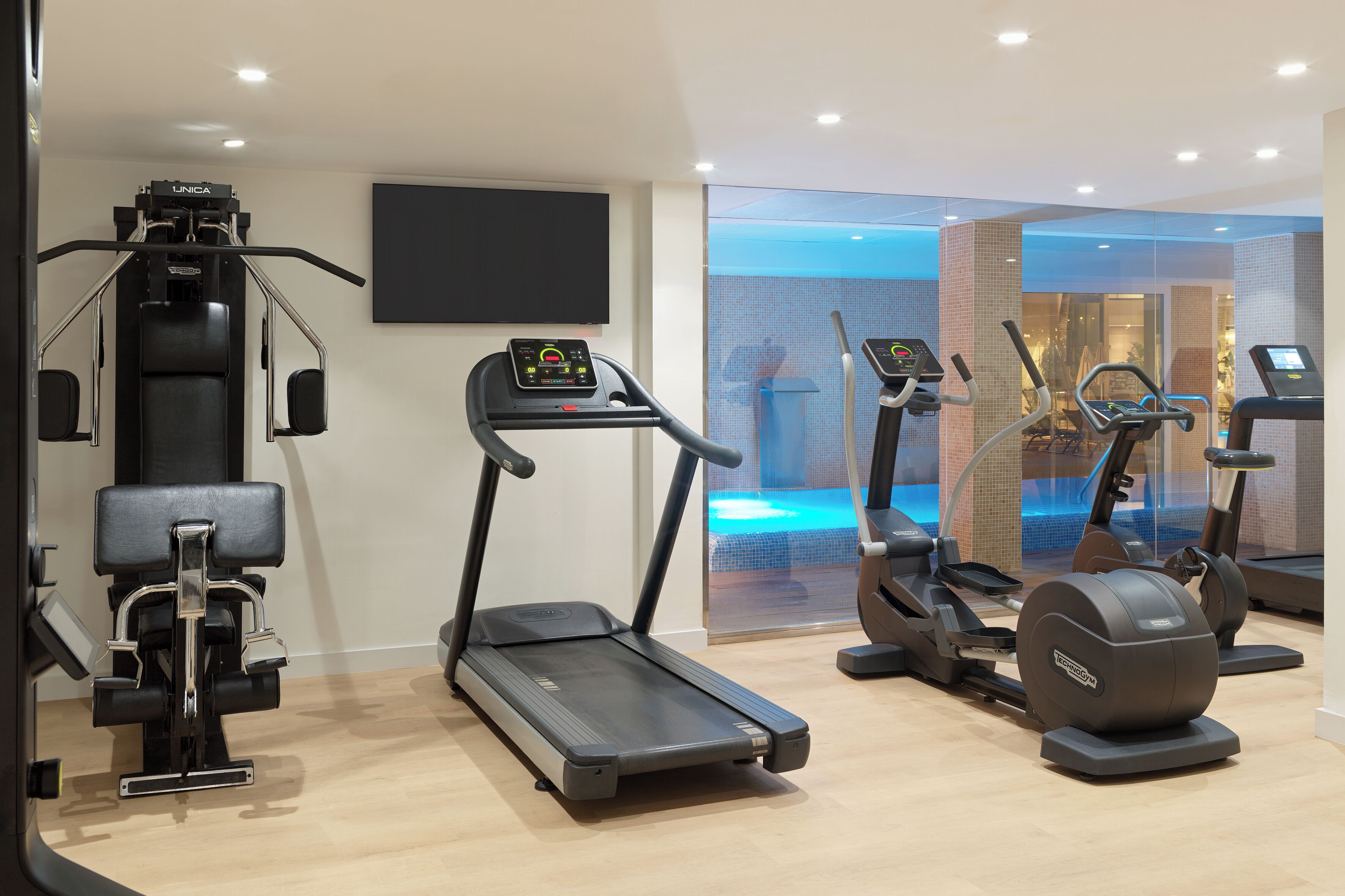 A modern gym with a treadmill, elliptical, and weight machine.