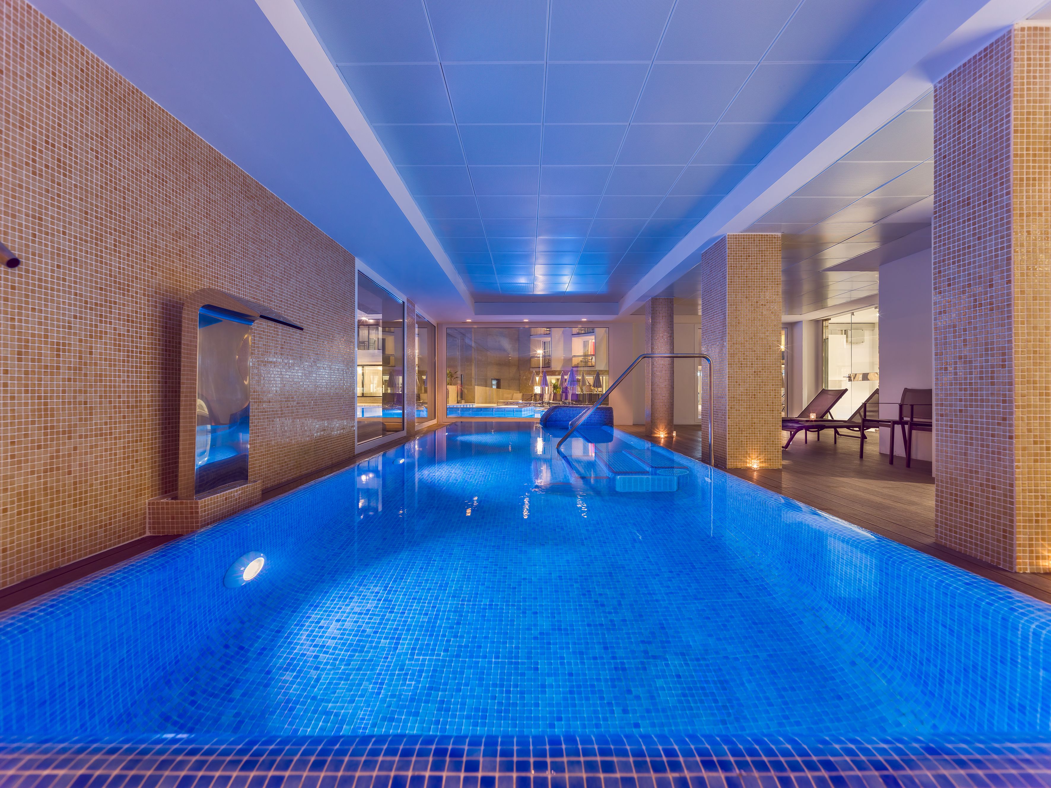 An indoor swimming pool with clear blue water, tiled walls, and a modern design.