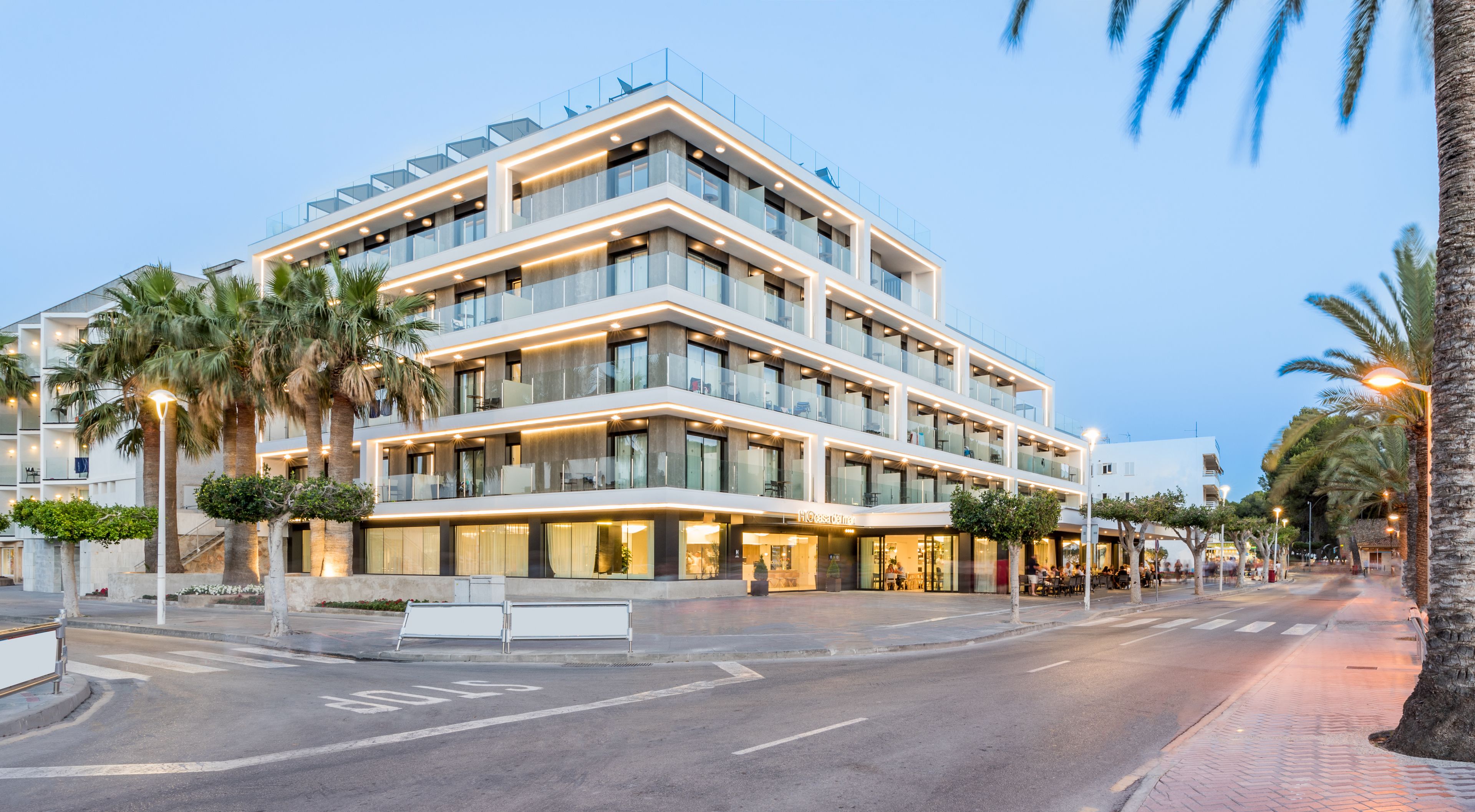 Un hotel de varios pisos con un diseño moderno, con balcones, ventanas amplias y una fachada bien iluminada.