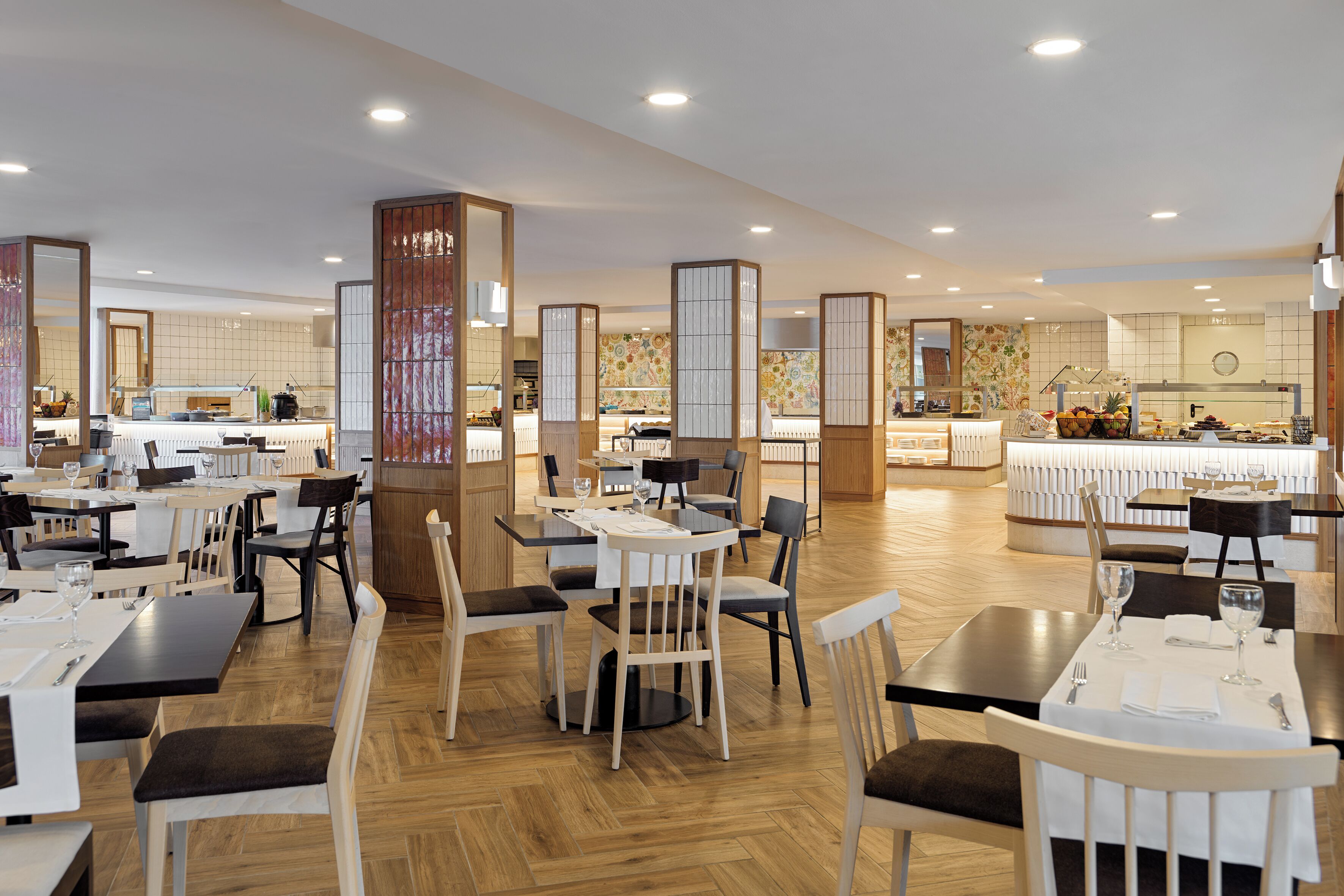 A spacious restaurant with multiple dining areas, wooden flooring, and a variety of seating options including tables and chairs.