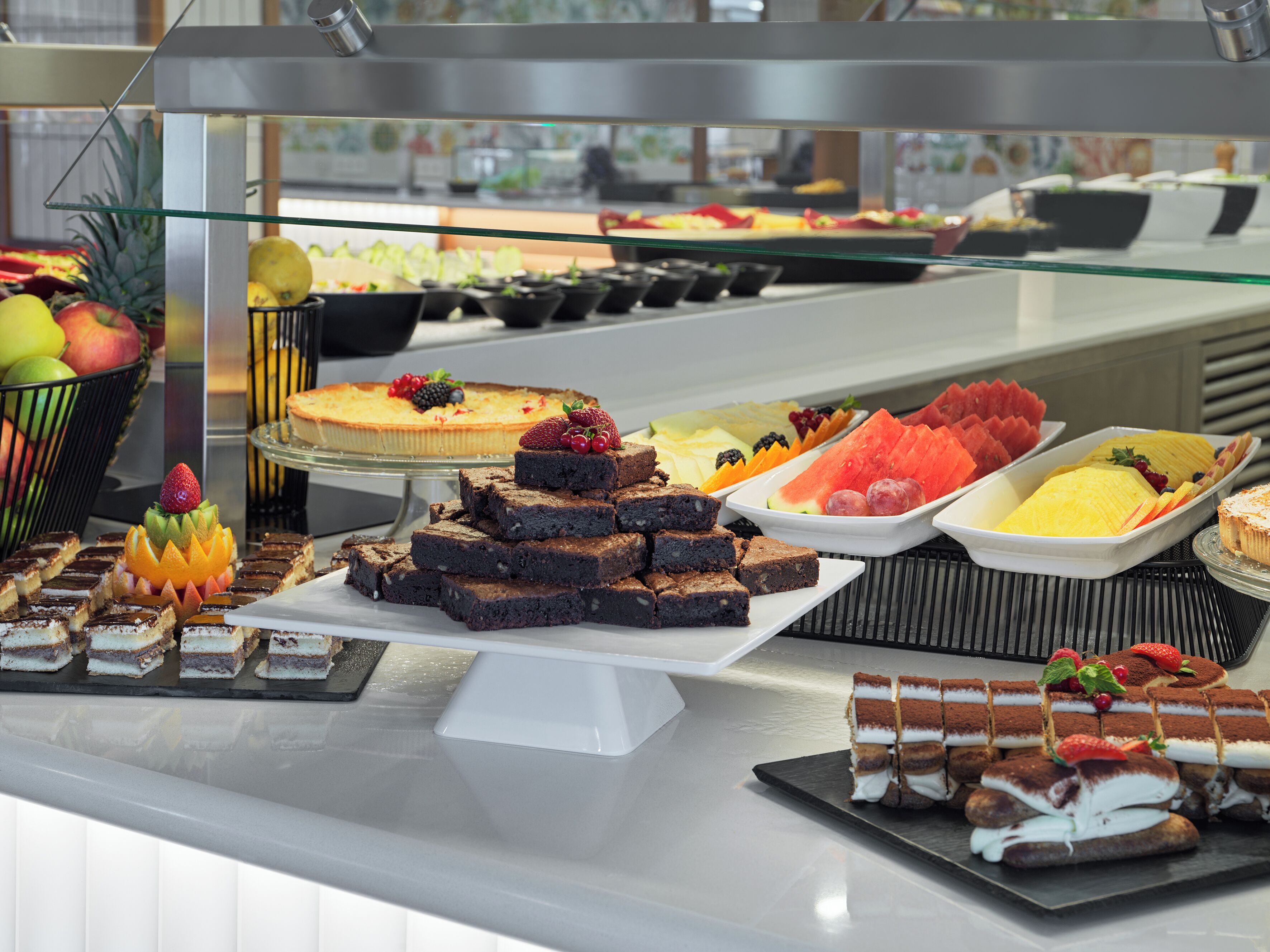 A buffet with various desserts and fruits.