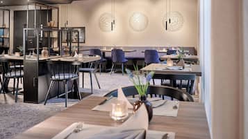 Un comedor moderno con varias mesas y sillas, un aparador de vidrio y decoración mural.