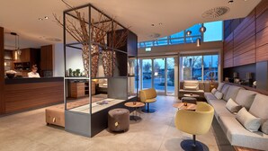 Un interior moderno con zona de estar, mostrador de recepción y vistas al exterior.