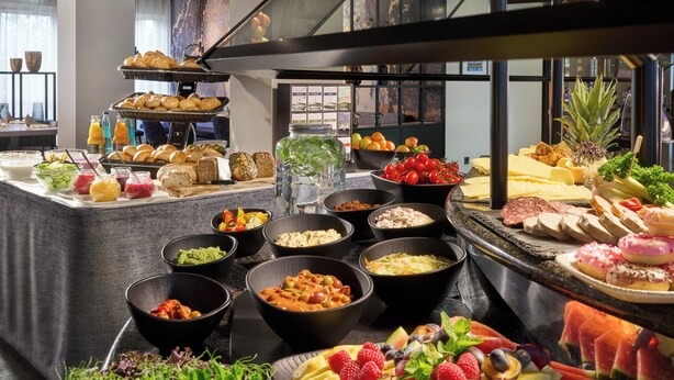 Un bufé con diversos alimentos, como frutas, quesos y embutidos.