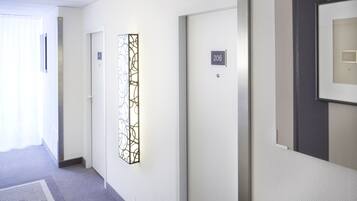 Un pasillo con una puerta identificada como 206, un panel decorativo en la pared y un cuadro enmarcado.