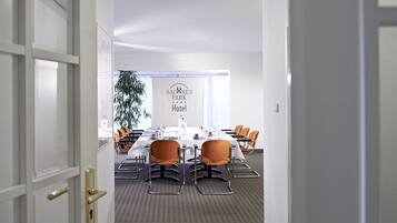 A conference room with a long table, chairs, and a sign for Sacsen Park Hotel.