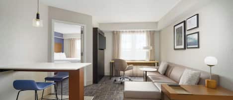 Une chambre d’hôtel moderne équipée d’une kitchenette, d’un canapé, d’un bureau et d’une chaise.