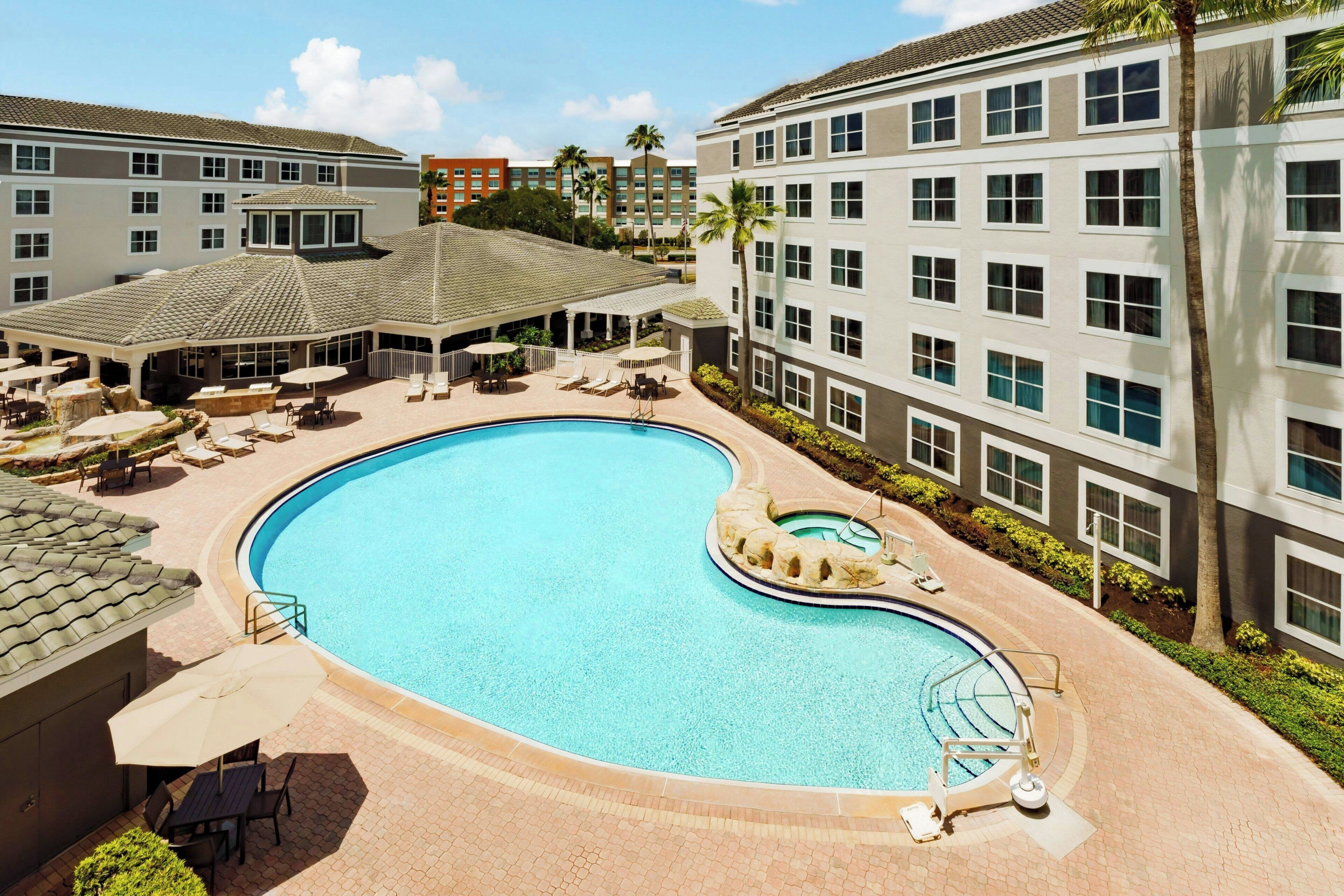 Un hôtel doté d’une piscine, de chaises longues et d’un patio couvert.