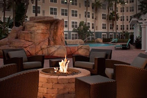 A poolside area with wicker furniture, a fire pit, and a large rock formation. - Residence Inn by Marriott Orlando Lake Buena Vista (Orlando)