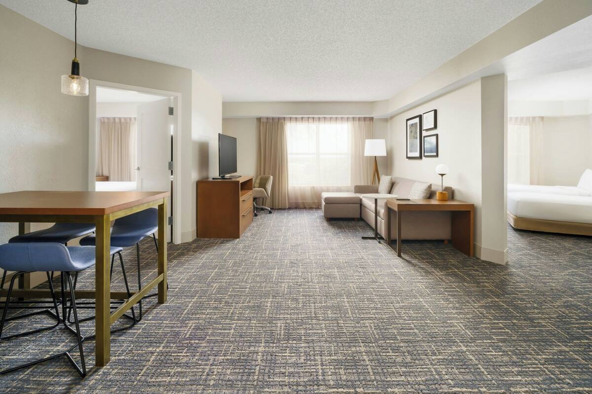 Ein Hotelzimmer mit Essbereich, einer Couch, einem Fernseher und einem Bett.