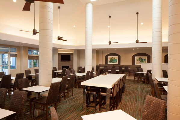 A spacious dining area with high ceilings, multiple tables and chairs, and ceiling fans. - Residence Inn by Marriott Orlando Lake Buena Vista (Orlando)