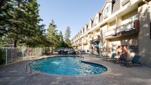A swimming pool with lounge chairs and a fenced area, surrounded by multi-story buildings. - Quality Inn South Lake Tahoe (South Lake Tahoe)