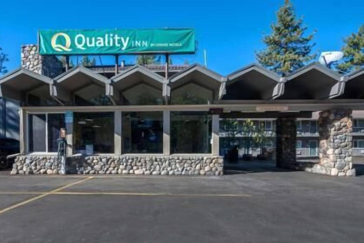 A hotel with a prominent green sign, stone facade, and multiple windows.