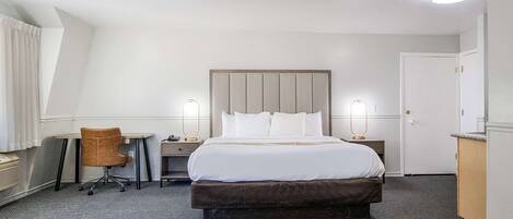 Une chambre d’hôtel avec un grand lit, un bureau, une chaise et une armoire.