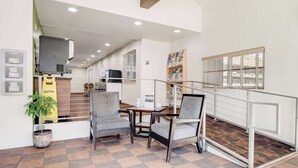 A modern hotel lobby with a check-in counter, seating area with patterned chairs, a staircase leading to upper floors, and a large window with blinds. - Quality Inn South Lake Tahoe (South Lake Tahoe)