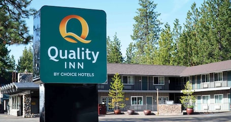 A Quality Inn sign with a logo and name, located in front of a two-story motel building with a stone facade and large windows.. Quality Inn South Lake Tahoe