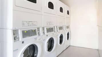 A row of stacked front-loading washing machines in a commercial setting.