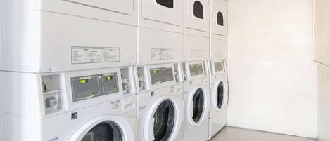 A row of stacked front-loading washing machines in a commercial setting.