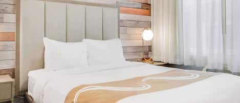 Un lit bien fait, avec du linge de lit blanc et un plaid beige, une lampe de chevet et un lambris en bois.