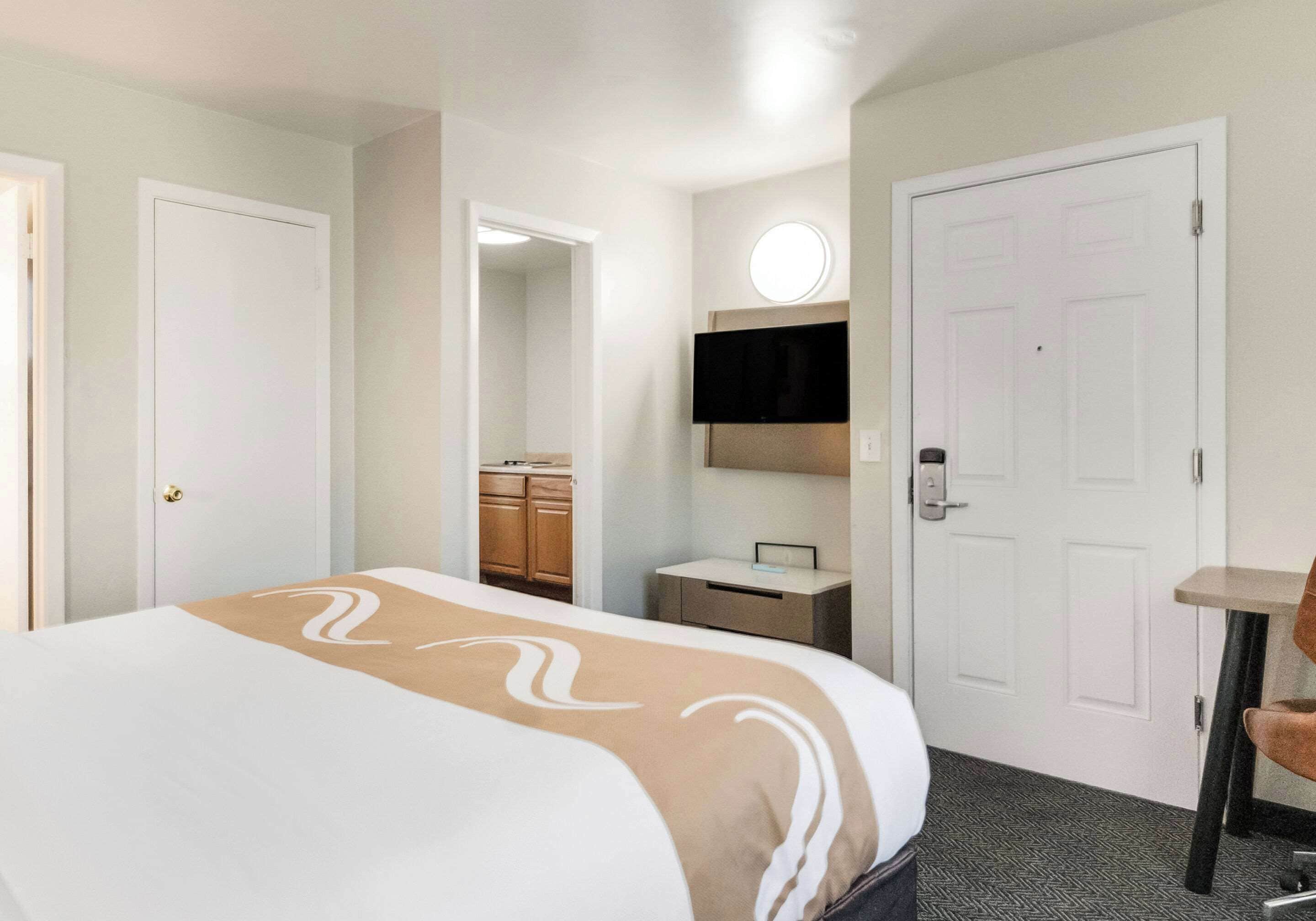 Une chambre d’hôtel équipée d’un lit, d’un bureau, d’une chaise, d’une télévision et d’une armoire.