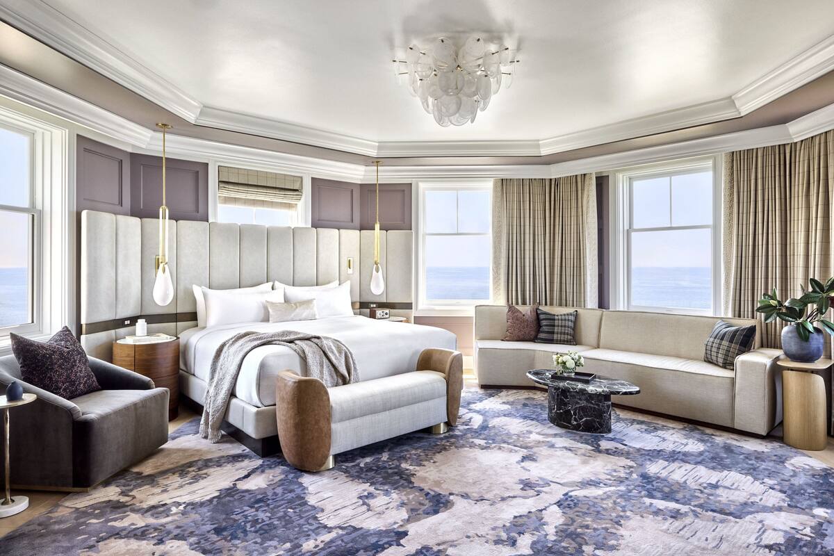A spacious bedroom with a large bed, a seating area, and a view of the ocean.