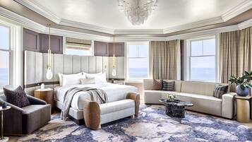 A spacious bedroom with a large bed, a seating area, and a view of the ocean.