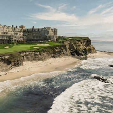 A large, multi-story hotel with a golf course and beach views.