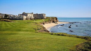 A large, historic building with a well-maintained lawn and a golf course in the foreground. - The Ritz-Carlton, Half Moon Bay (Half Moon Bay)