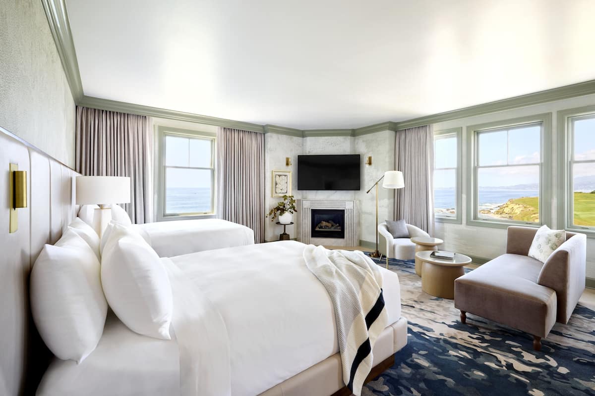 A hotel room with a large bed, a sofa, a TV, and a fireplace.