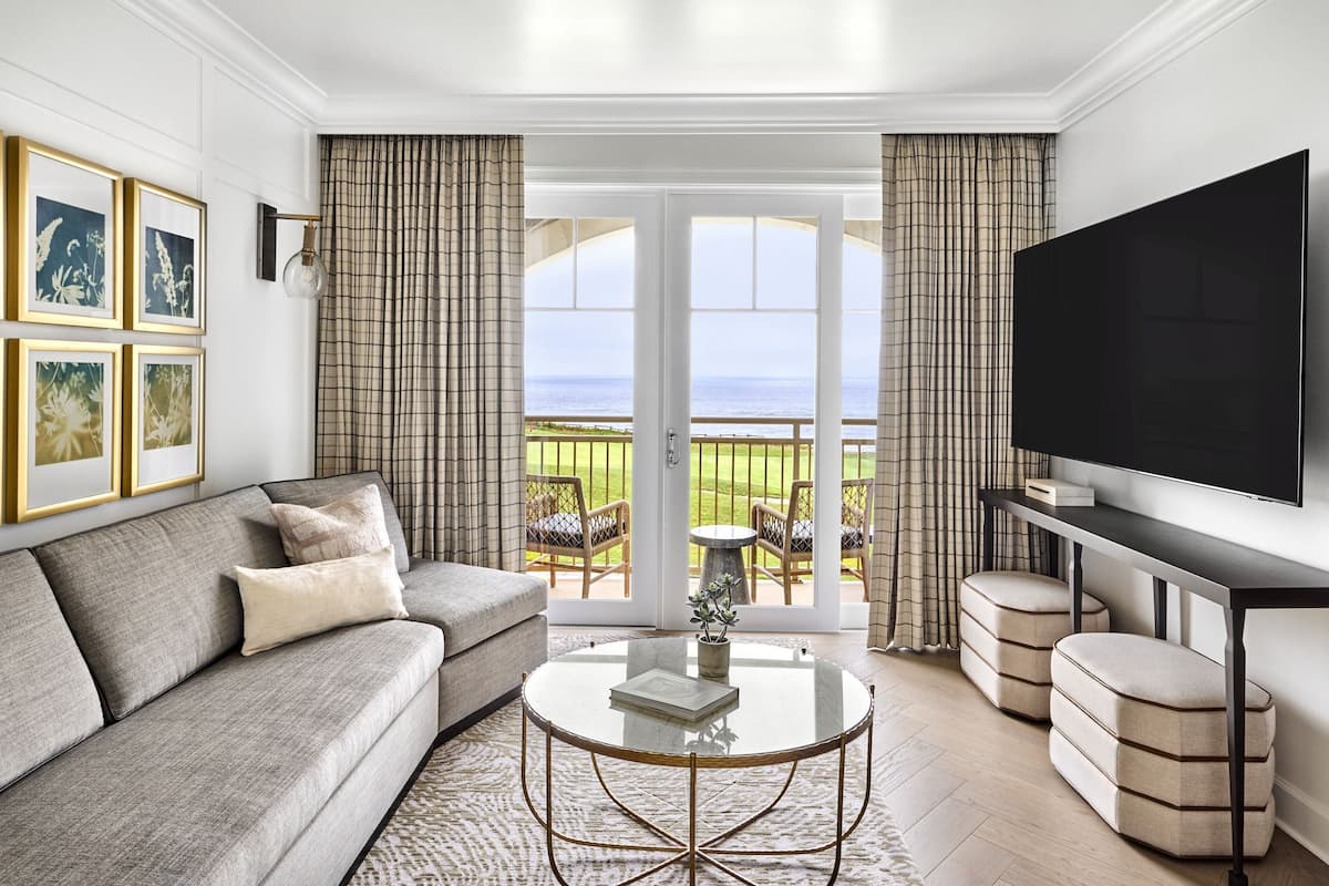 A living room with a sofa, a coffee table, a flat-screen TV, and a view of the outdoors.
