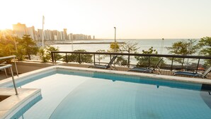 Piscina com revestimento em azulejo e vista do horizonte da cidade ao fundo.