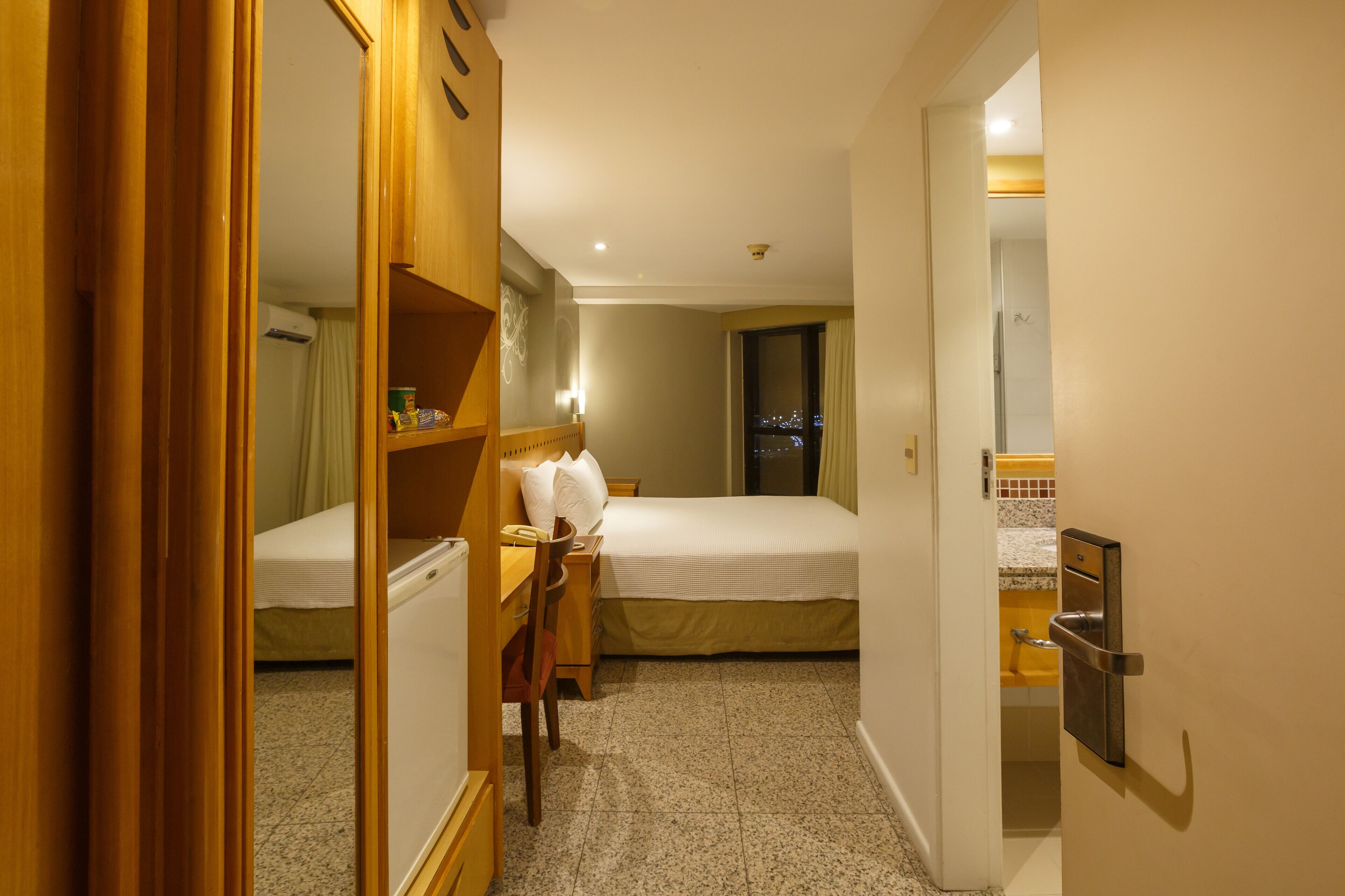 Une chambre d’hôtel comprenant un lit, un bureau, une chaise et une armoire.