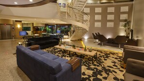 Um hall amplo com área de estar central, uma escada em espiral e vista para a cozinha.