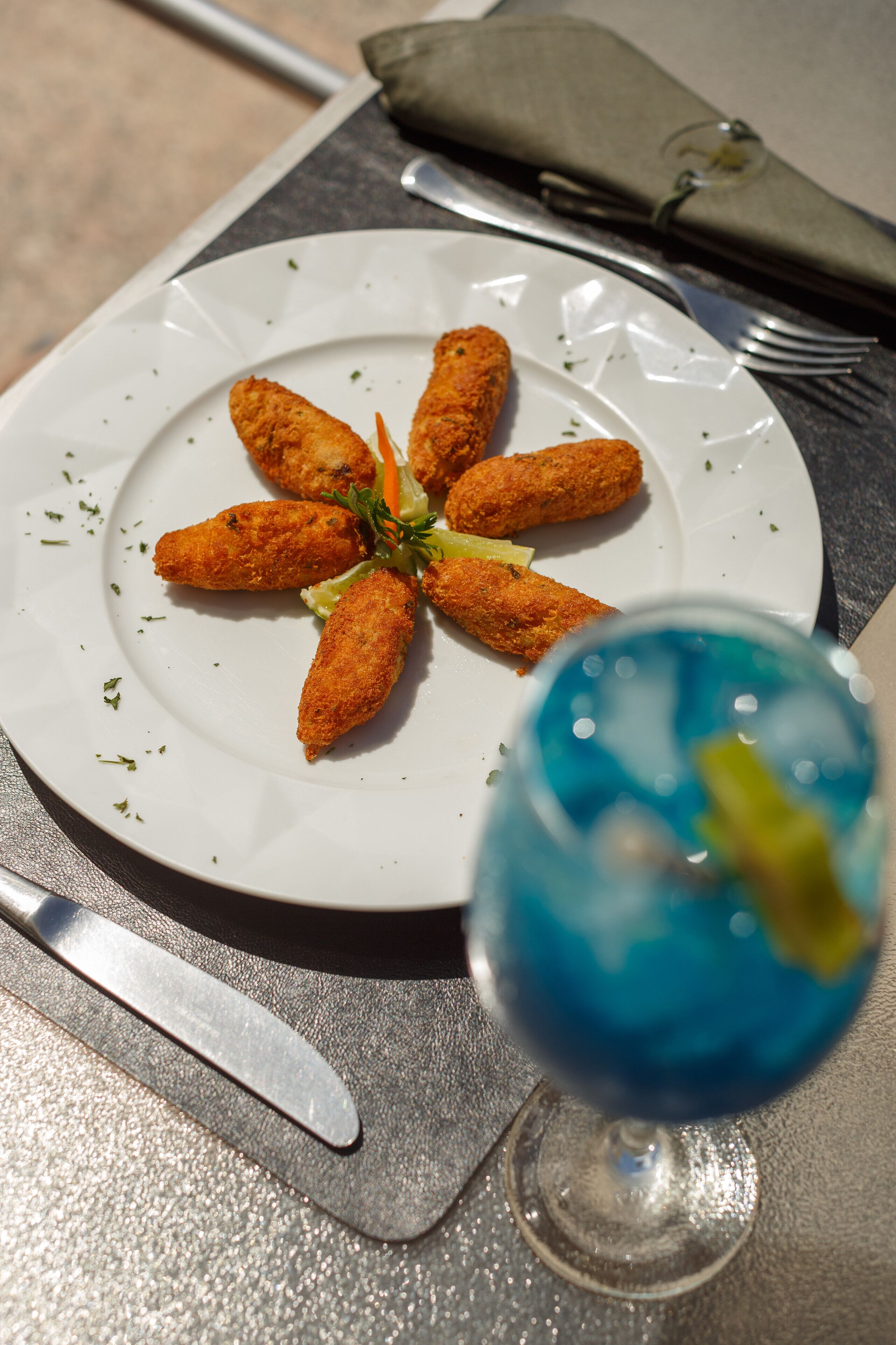 Une assiette de nourriture et un verre d’une boisson bleue sont posés sur la table.
